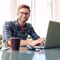 Male student at laptop smiling at camera