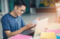 Young student smiling while working at his laptop