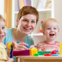 Smiling woman playing with two children in a daycare setting