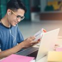 Young student smiling while working at his laptop