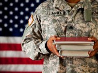 Military member holding textbooks in front of American flag