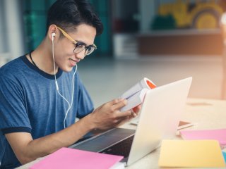 Young student smiling while working at his laptop